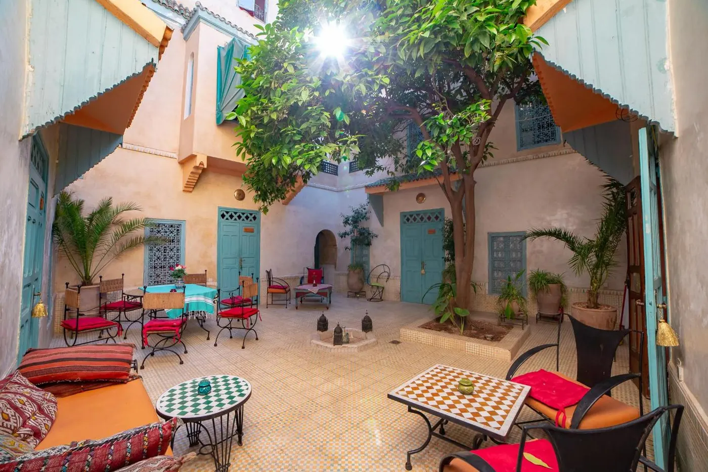The patio in the sun: orange tree, tables and painted doors